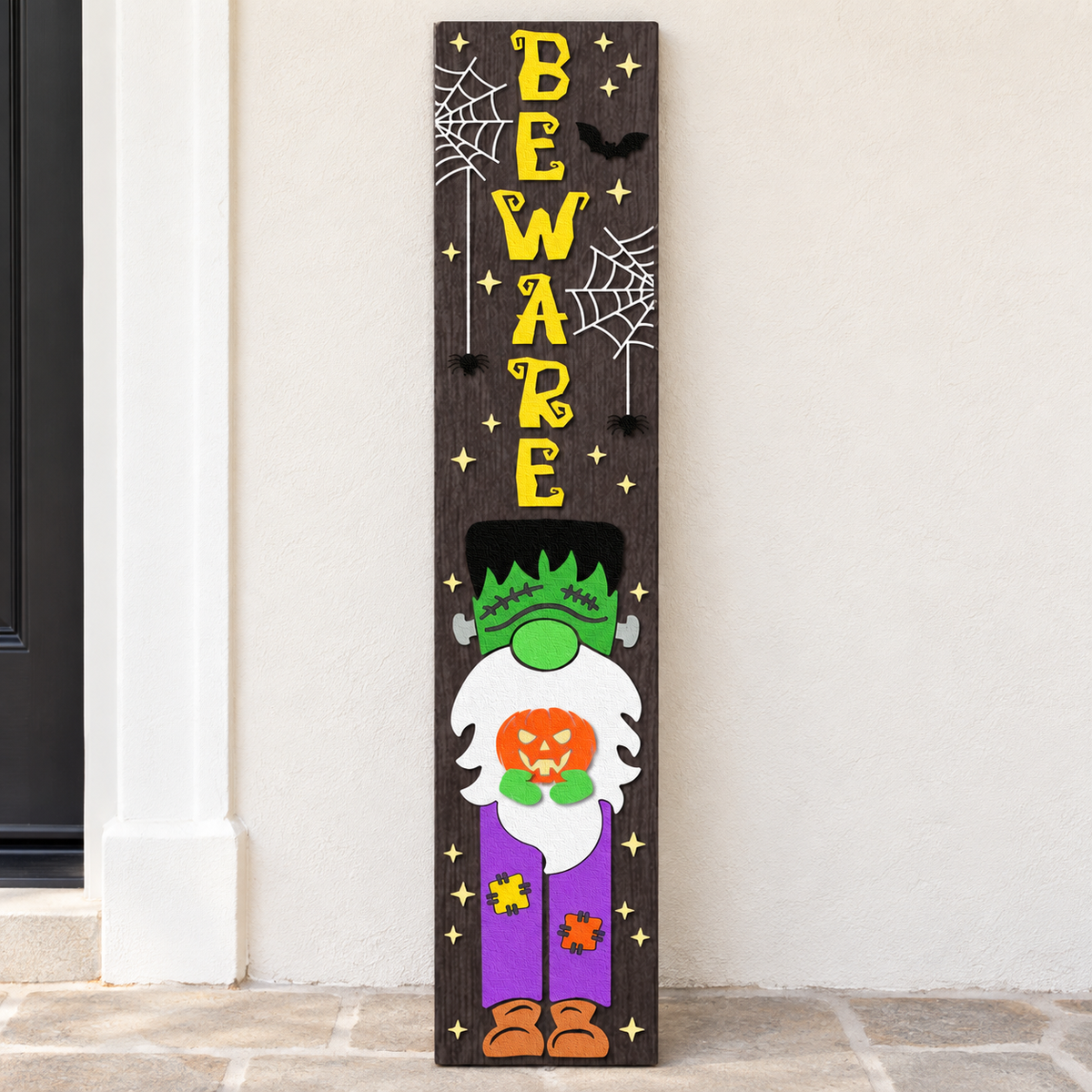 Full view of the Beware Frankenstein gnome sign with yellow lettering, spiderwebs, and a bat